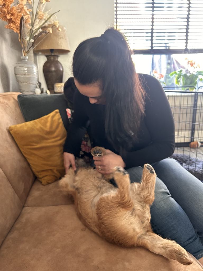 Eva knuffelt liefdevol met een kleine, ontspannen hond op de bank