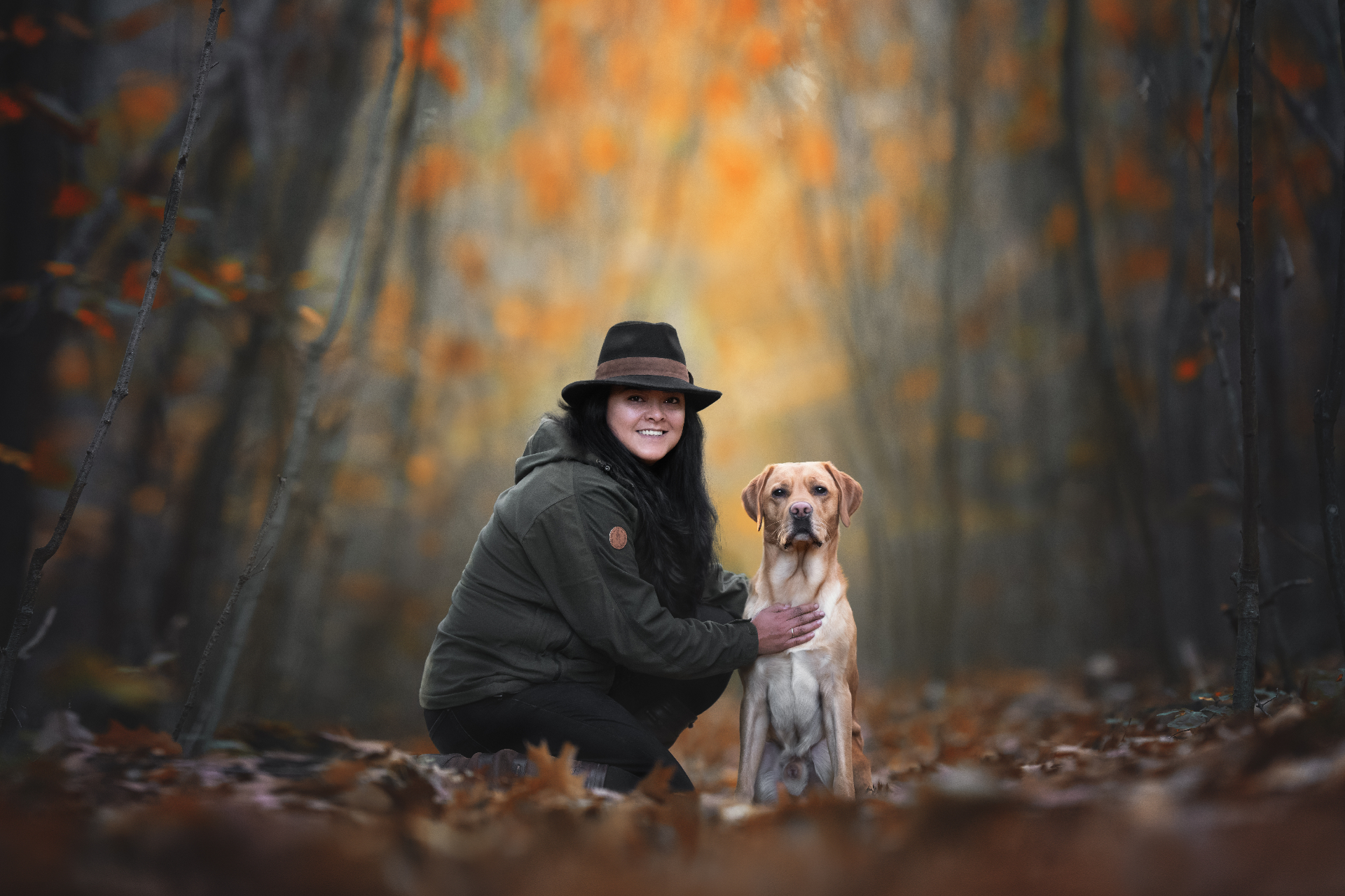 Eva Roosendaal knielt in een herfstbos naast een blonde labrador